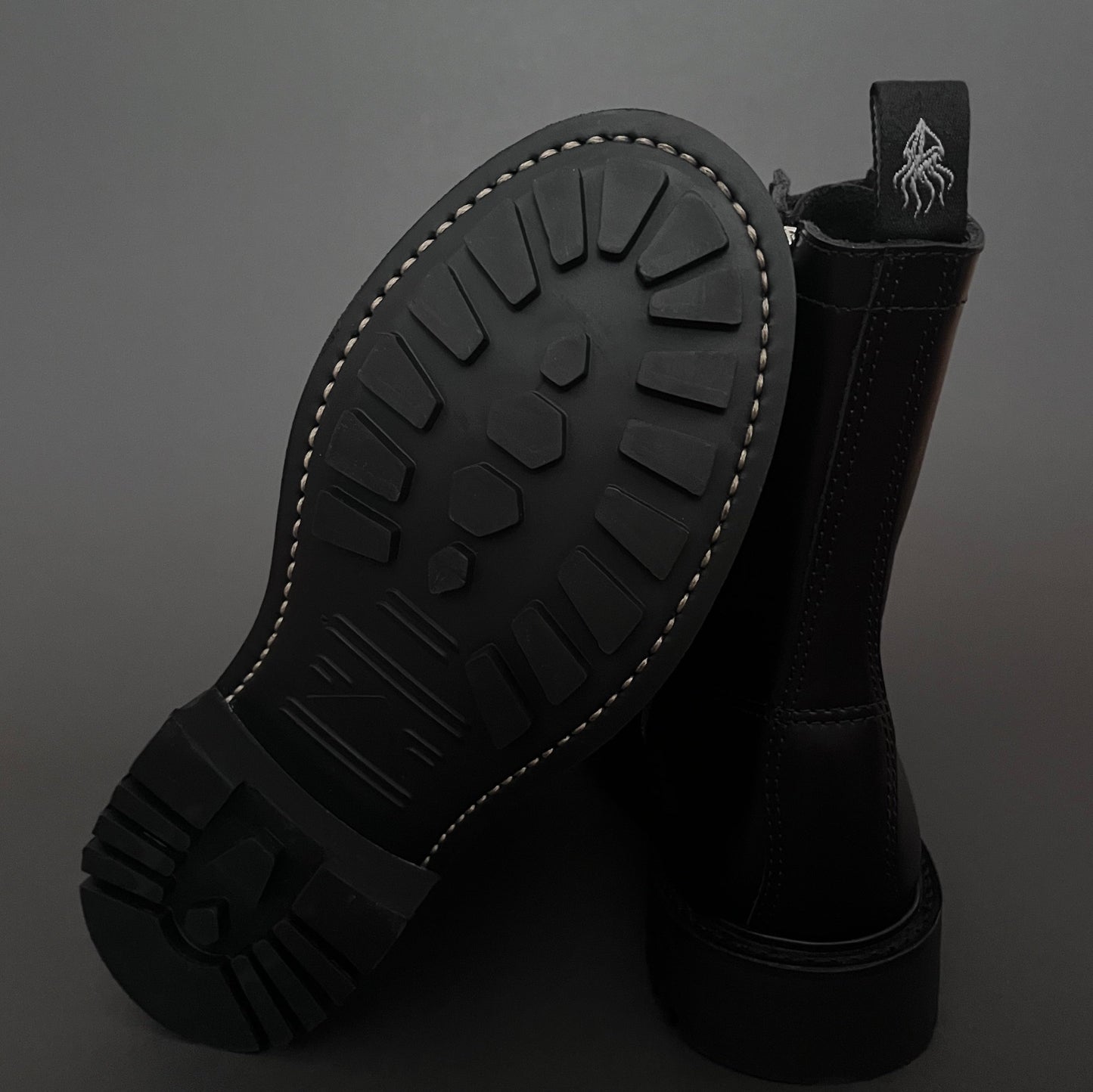 Black boot with sole showing tread pattern on a dark background