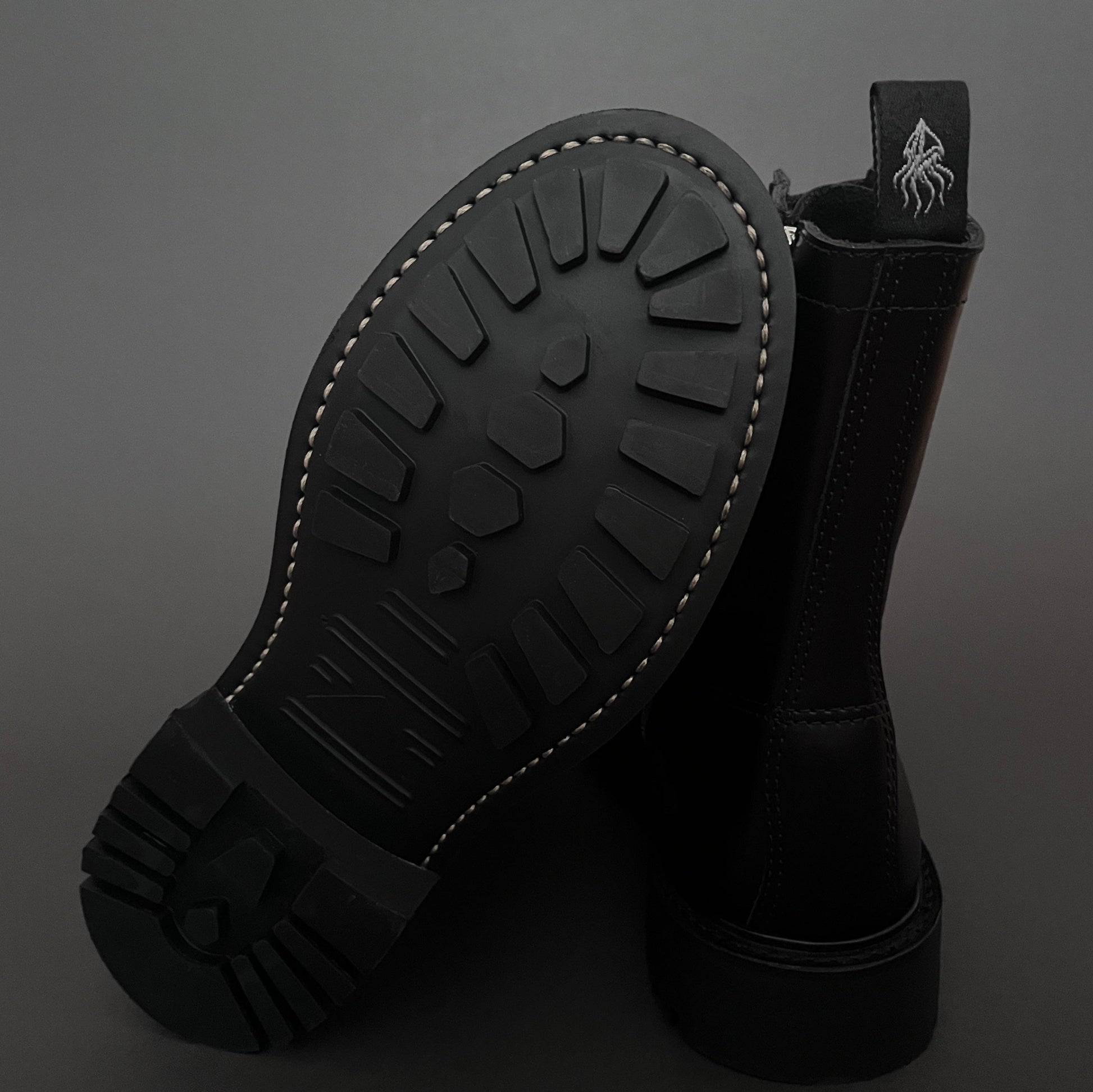 Black boot with sole showing tread pattern on a dark background
