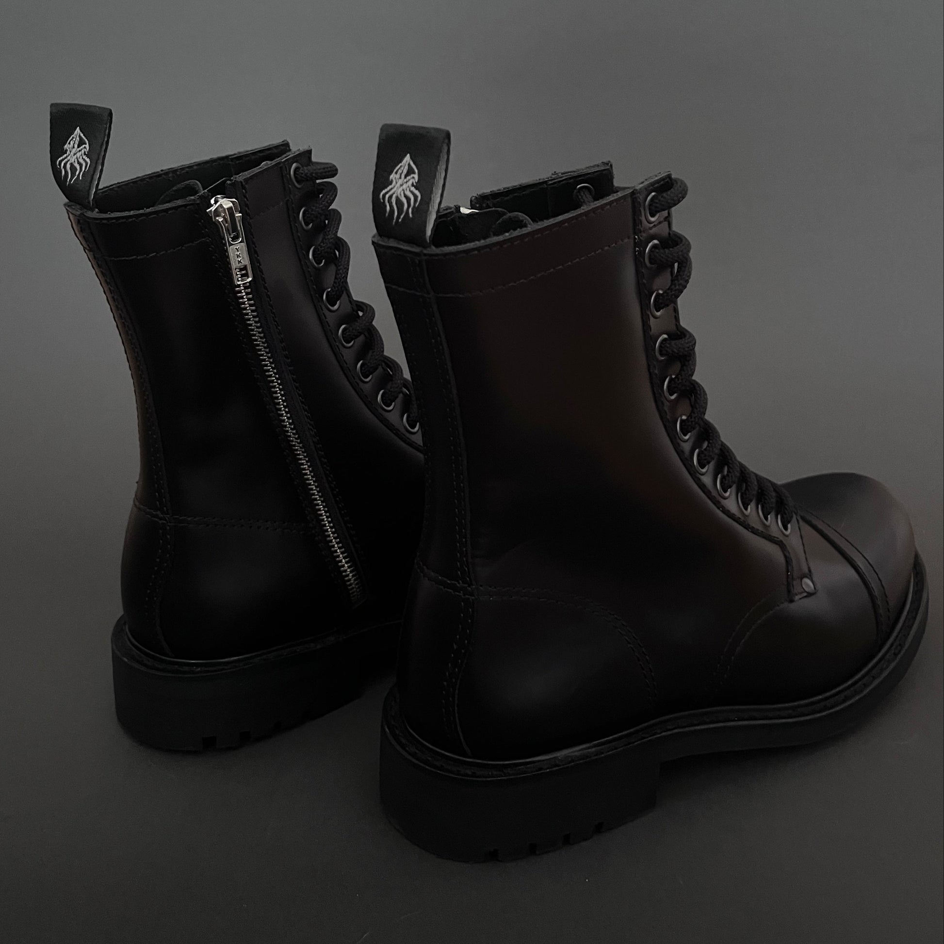 Pair of black boots with a zipper on a dark background