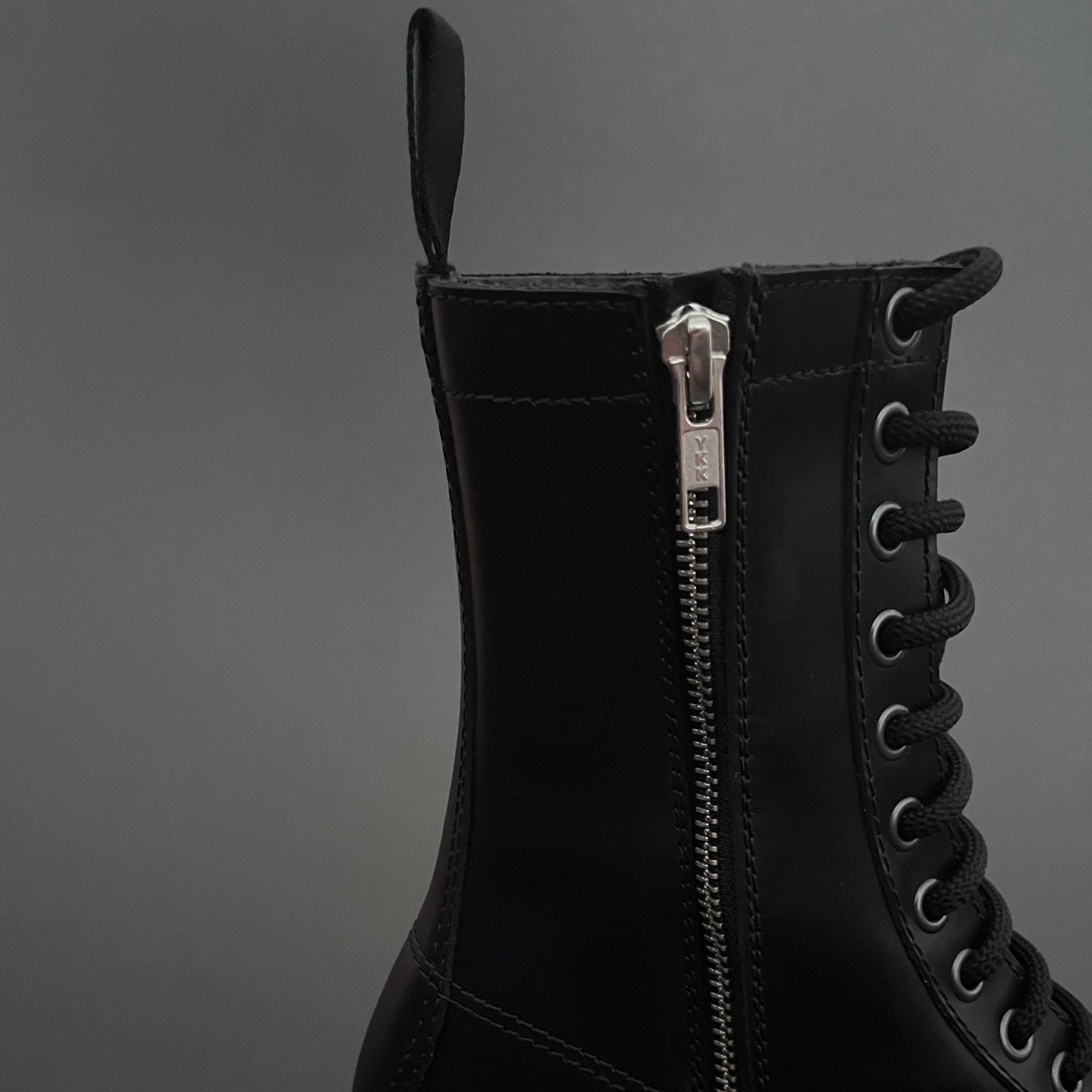 Black boot with a zipper on a gray background